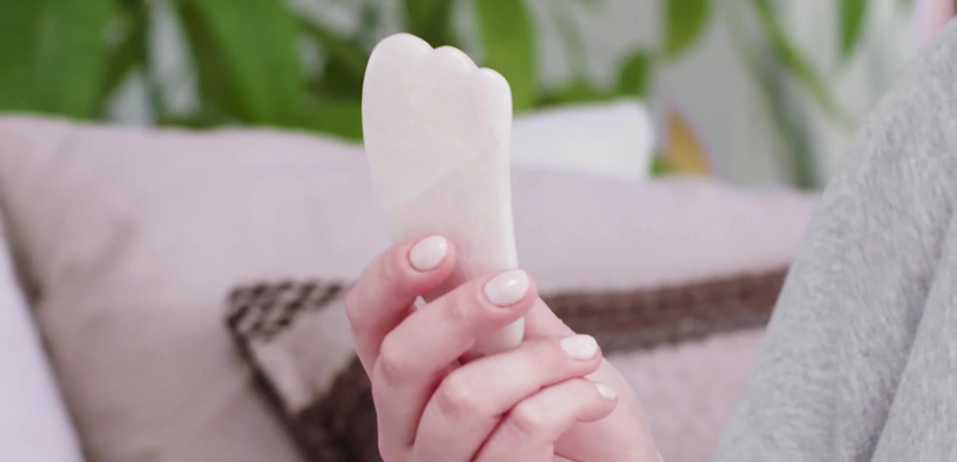 The presenter holding and demonstrating a Gua Sha tool.