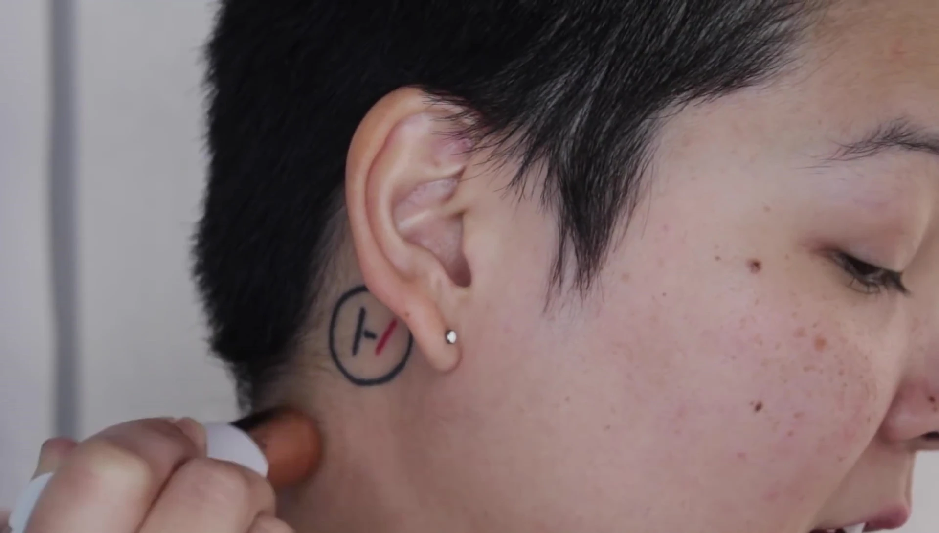 The reviewer using the device near their eyebrows with caution.