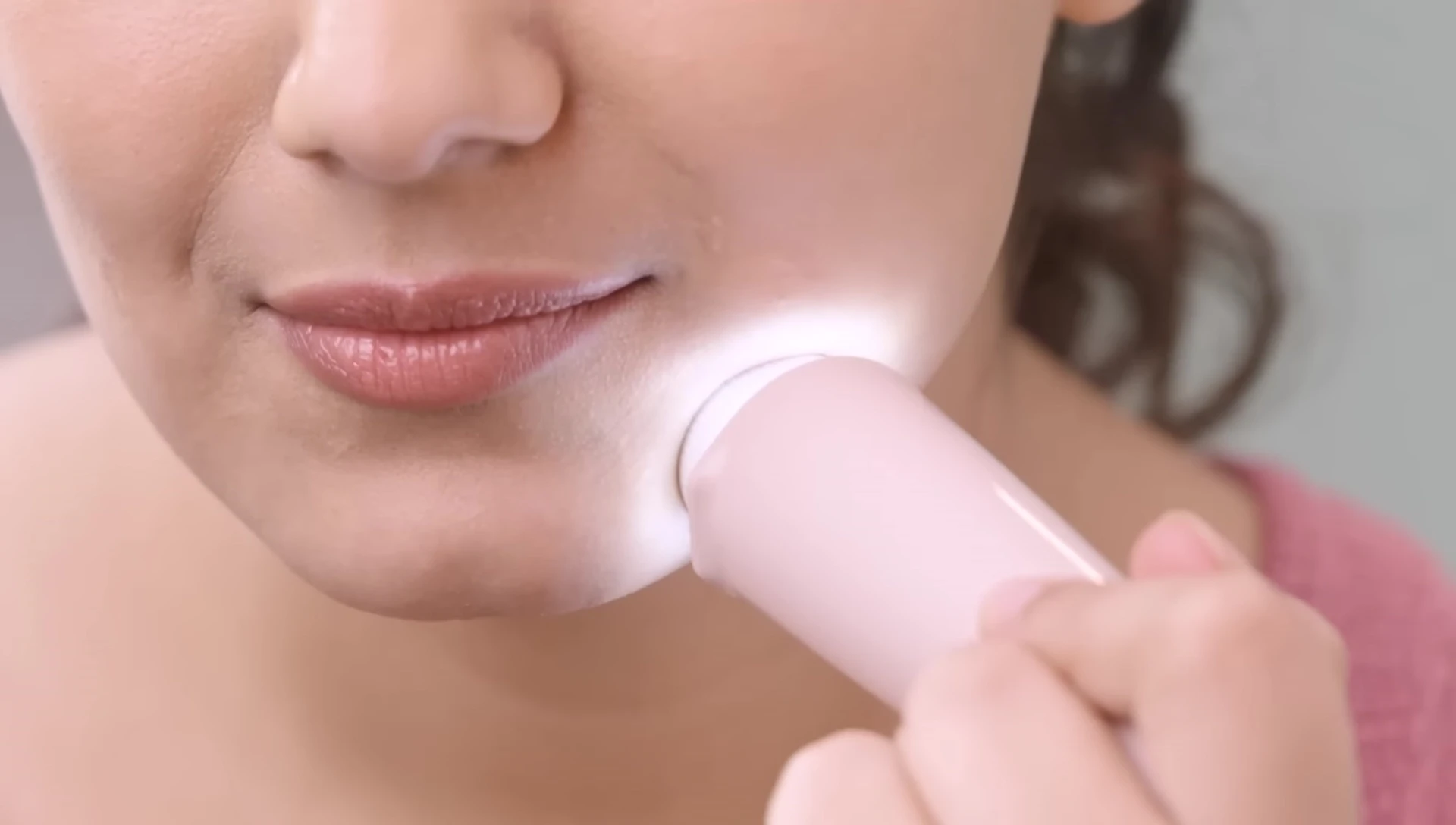 Woman using the Philips facial hair remover with the LED light illuminating the area